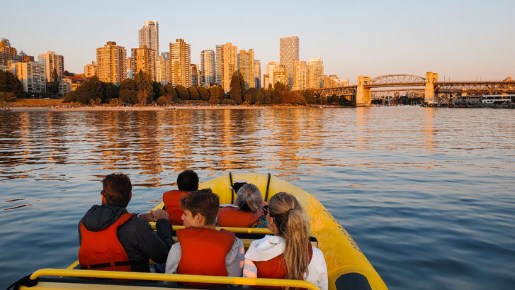 a family in a yellow boat on the sea with a view of Vancouver's skyline