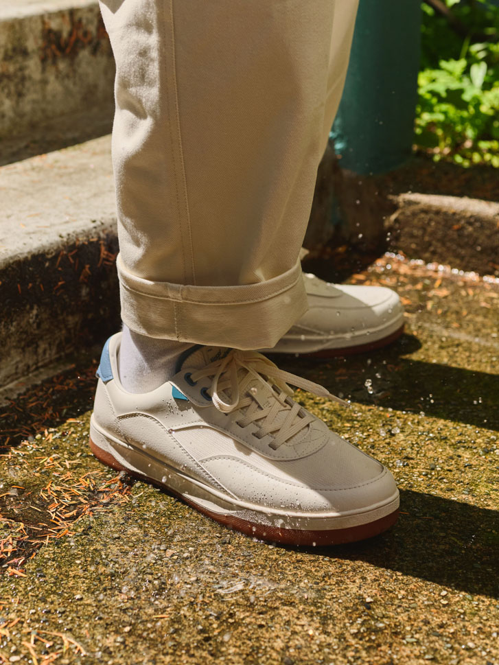 a guy's legs in folded cream pants and cream sneakers