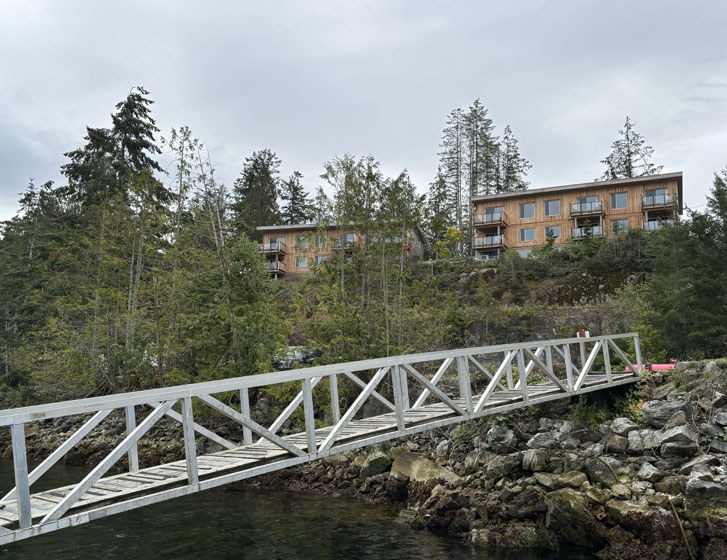 a boardwalk across a river and villas on the other end of the boardwalk