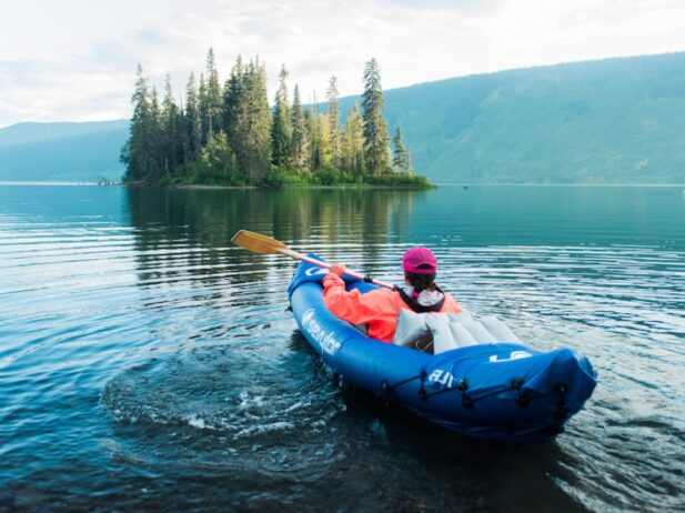 woman canoeing and kayaking with a paddle in her hand on a large lake with the hills around