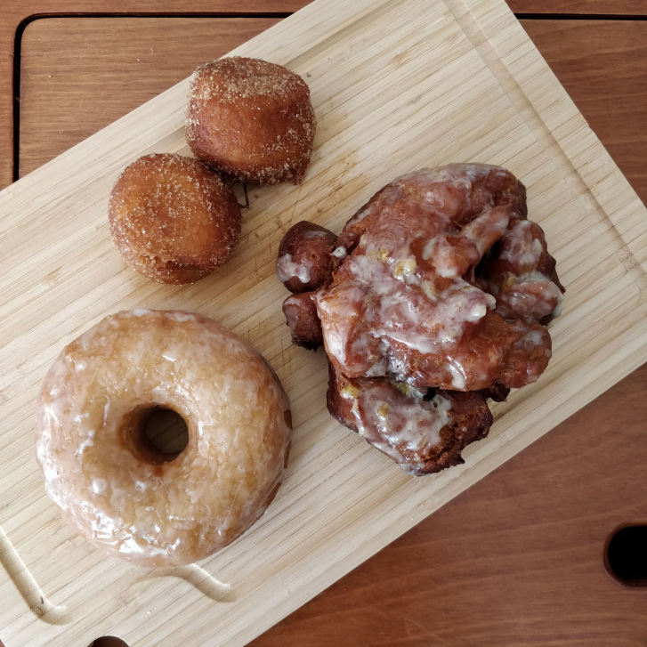 top view of three different brown donuts on a wooden cutting board