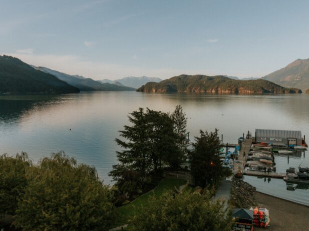 aerial view of a huge lake and the green hills around with a walkway leading to a dock on the lake