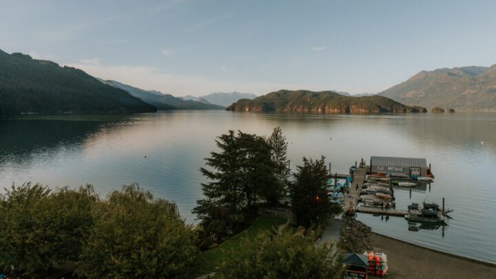 aerial view of a huge lake and the green hills around with a walkway leading to a dock on the lake