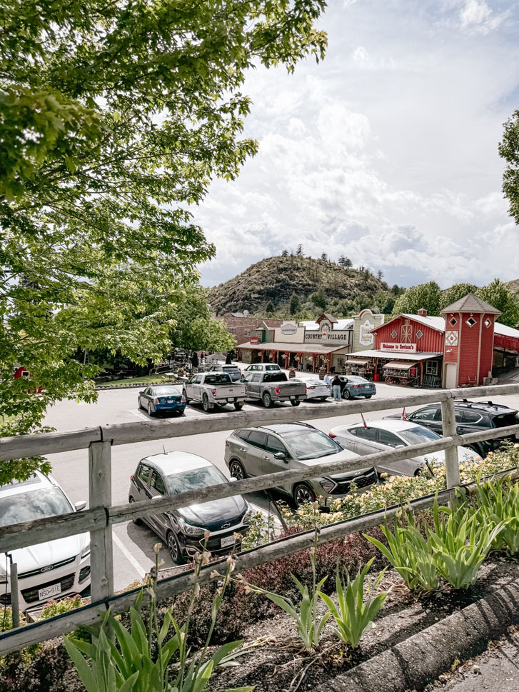 a car park full of parked cars beside a farmer's market building 