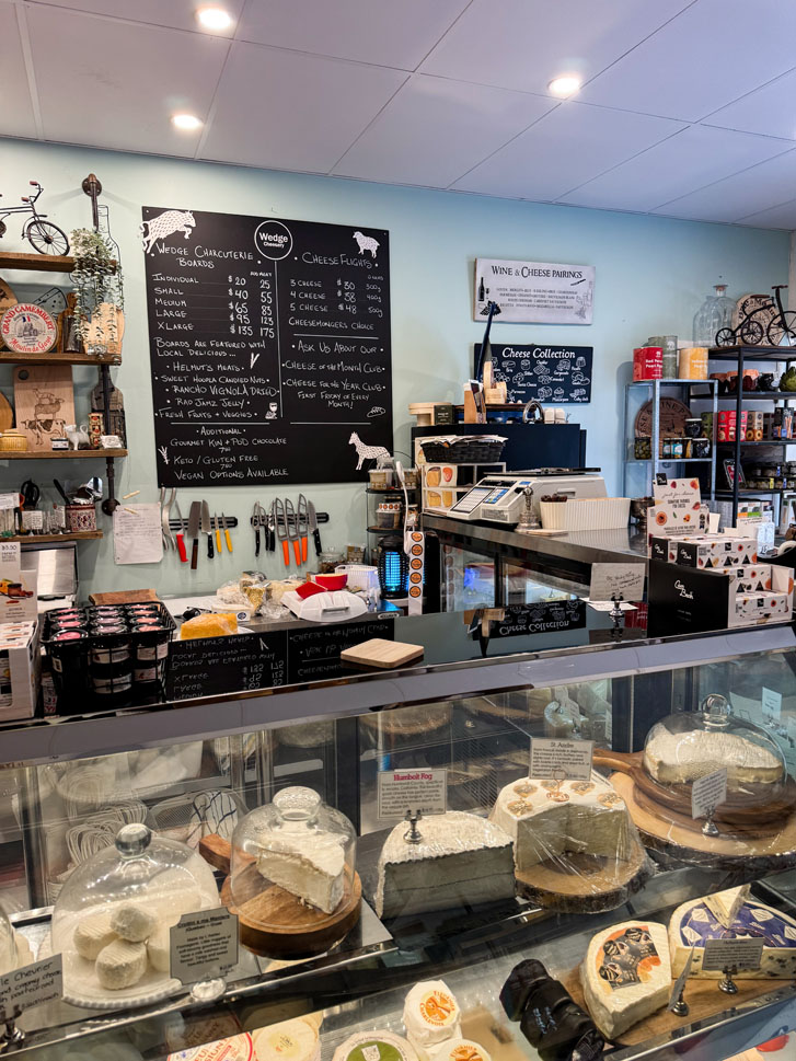 variety of cheese in a showcase with menu board in view