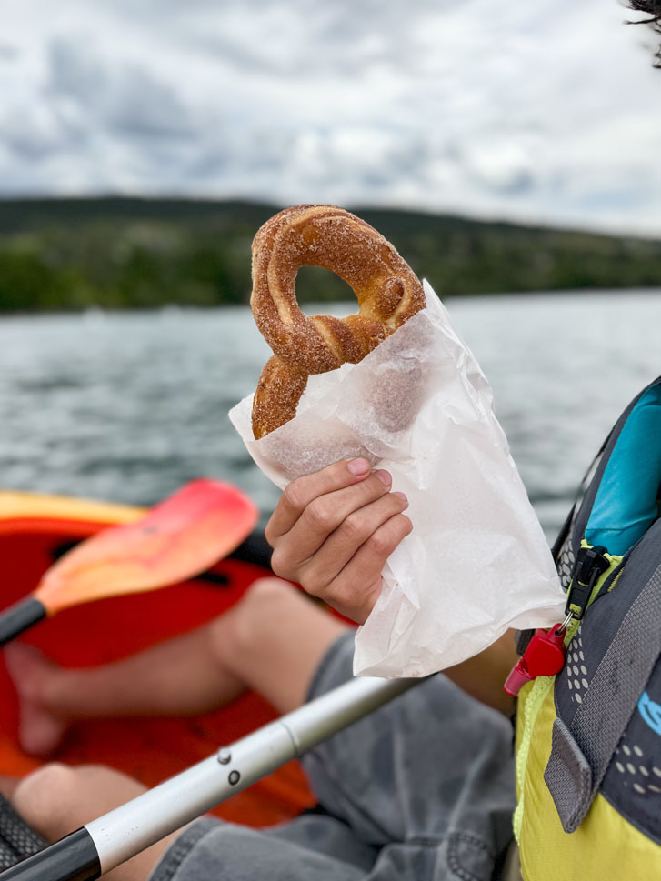 someone holding cinnamon rolls while in a paddle boat on a lake