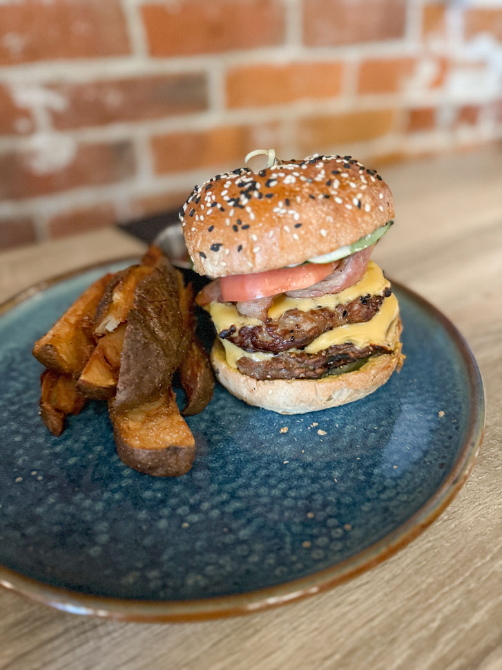 a plate of steak burger with potato slices beside it