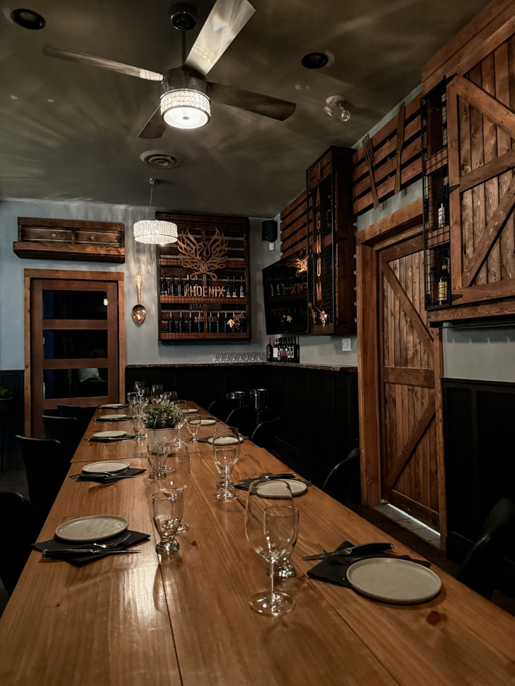 a wooden themed room with a wooden table having plate and glasses spread apart on it