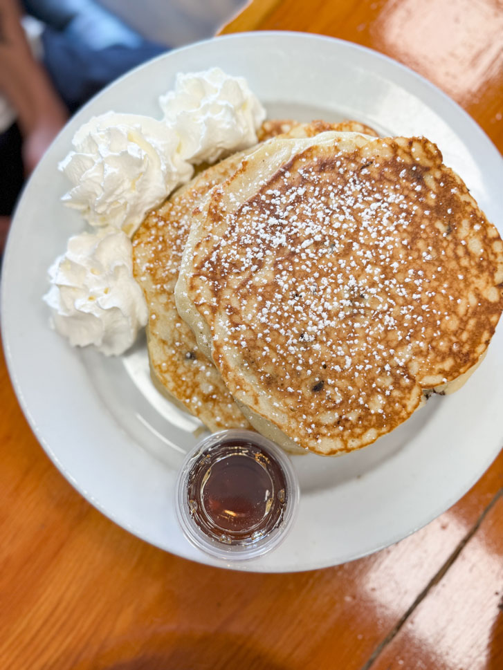 a plate of pancakes and icing balls on the side with a plate of sauce