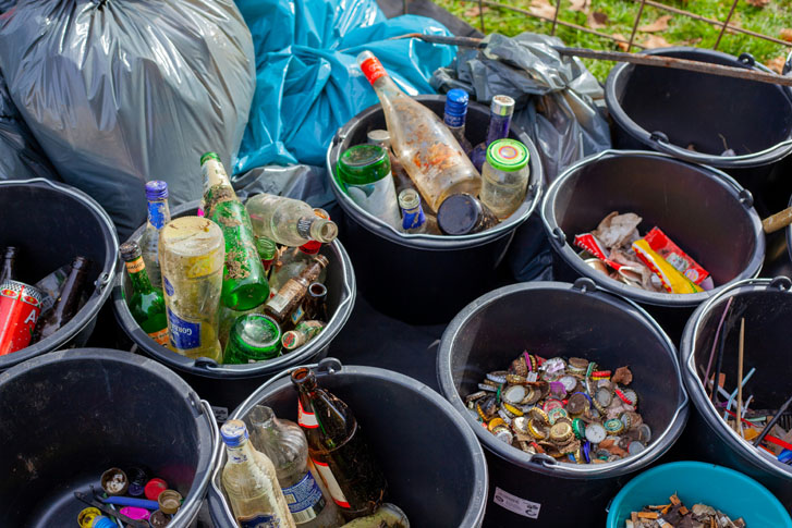 rows of trash buckets containing piles of dirty empty bottles and jars with some containing drink caps