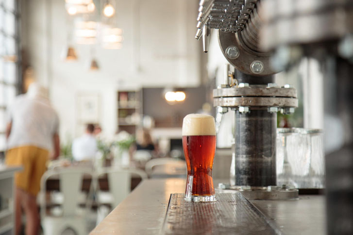 a tall glass of beer at a drink dispenser stand