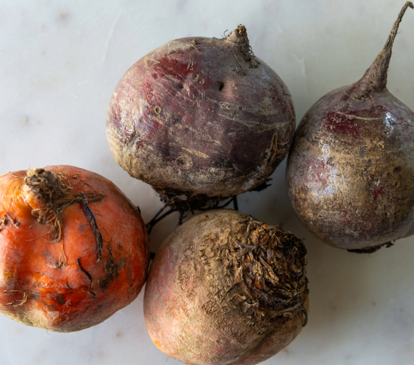 four red and white beets on a white countertop