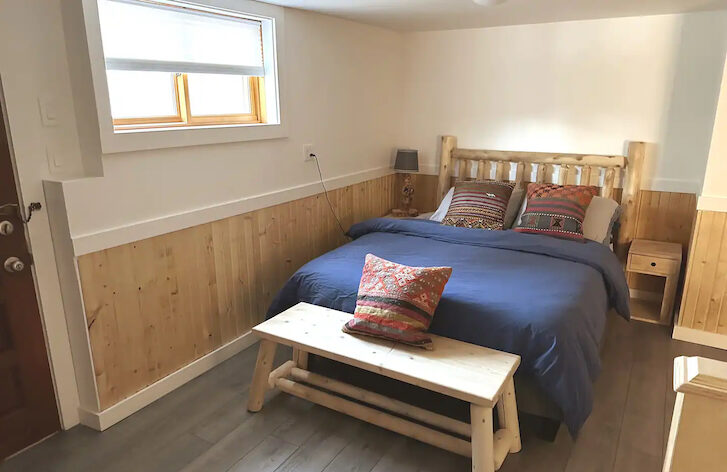 a bedroom with a bed and wooden seating are at the foot of the bed