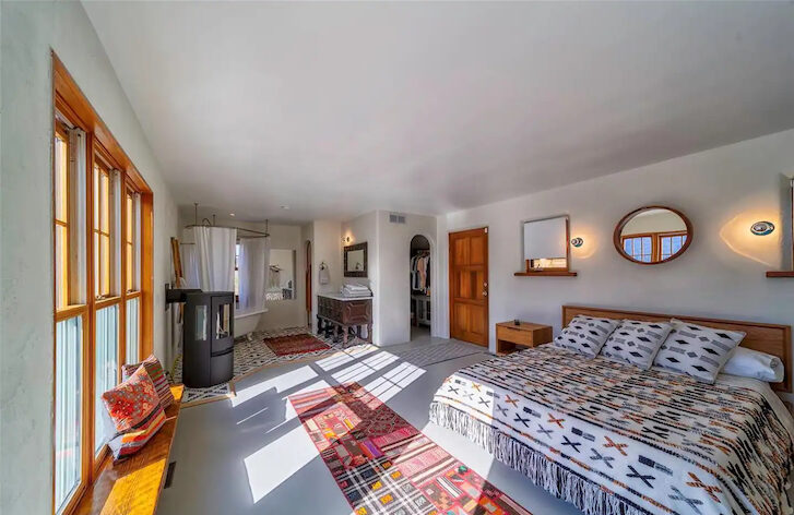 a bedroom with a big bed, a floormat and huge windows