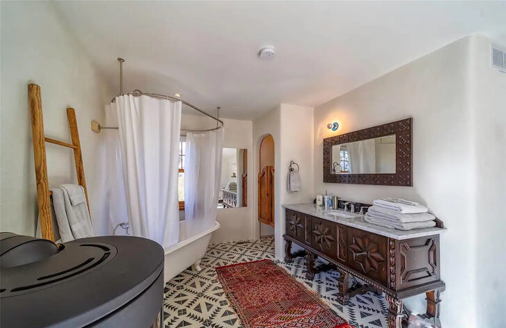 a bathroom with a mirror, wash basins and a bathtub