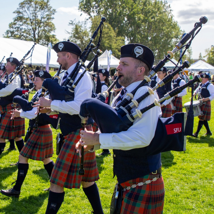 people walking playing the bag pipes in tartan dress